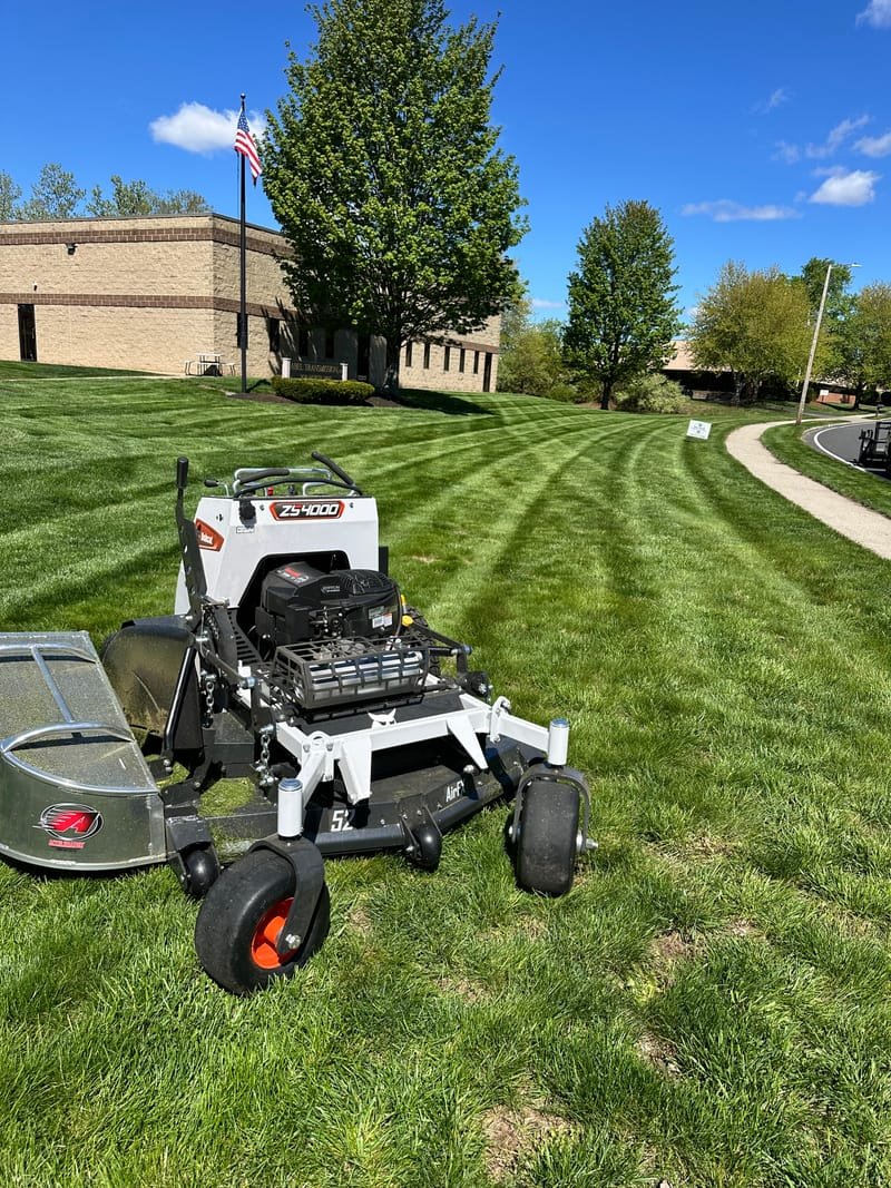 Zero-turn mower finishing a striped front lawn